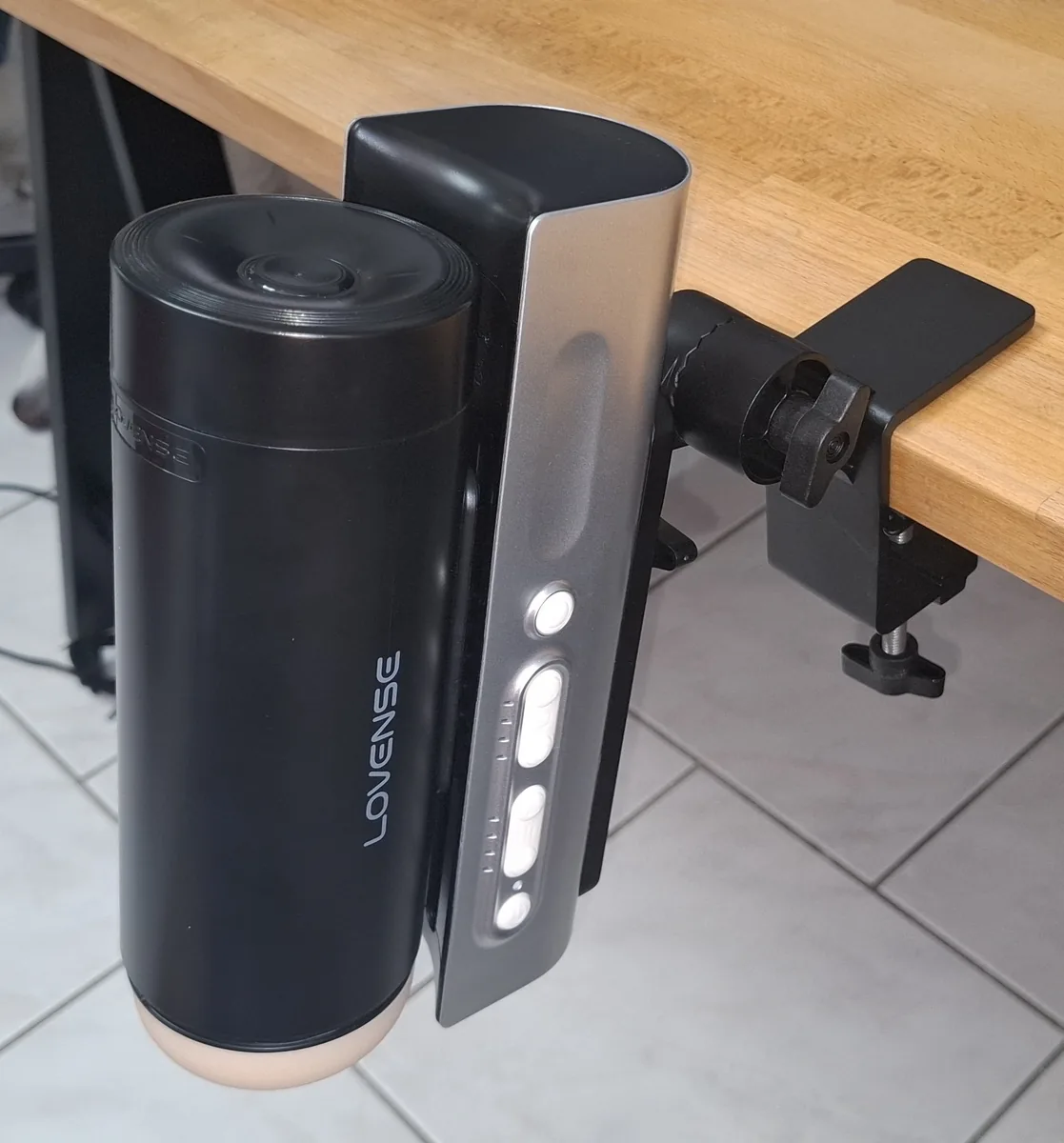 The Lovense Solace Pro clamped to the edge of a desk, running hands-free